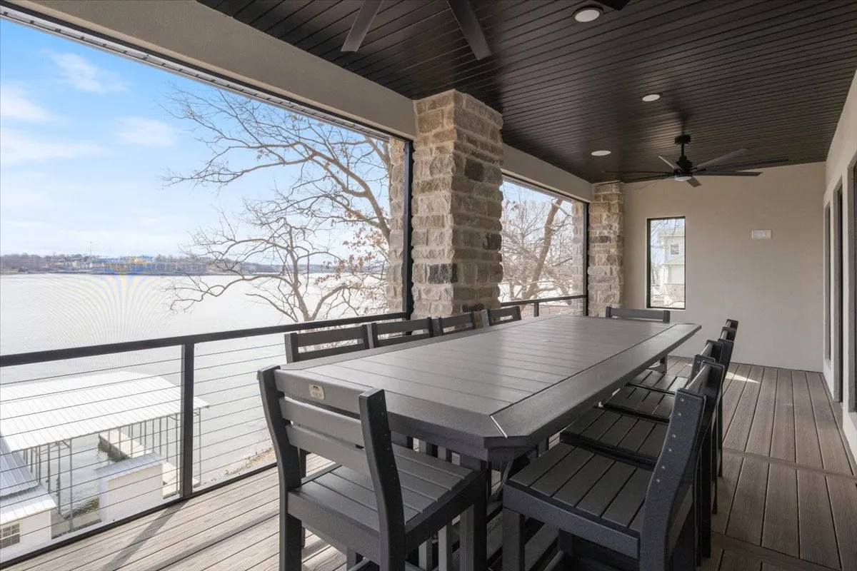 An inviting outdoor dining area with a large table, stone columns, and sweeping views of the water. The space is perfect for social gatherings, group meals, or cocktails overlooking the lake—mirroring the section’s emphasis on communal luxury.