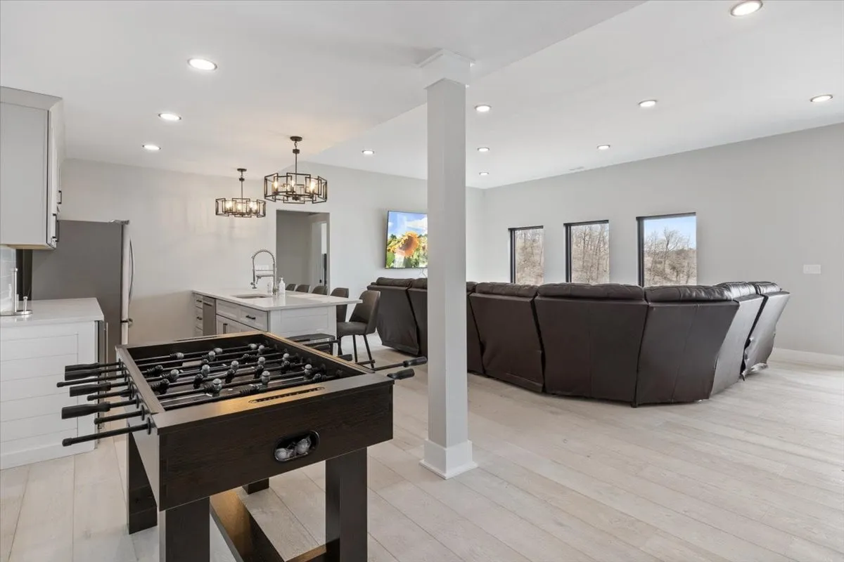 This image showcases a game room with a foosball table as the centerpiece, surrounded by a comfortable seating area and large windows that bring in natural light. The setup is ideal for socializing, playing games, and relaxing, perfectly capturing the playful and communal spirit described in the section.