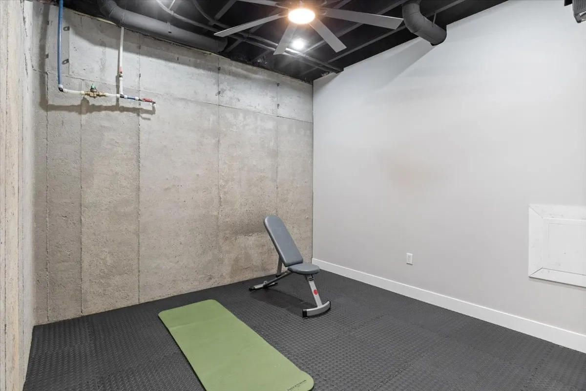 This image depicts a workout space with an exercise mat, weight bench, and concrete wall, evoking a sense of focus and motivation. It represents the in-home gym that will soon be part of the amenities, alluding to the wellness and fitness opportunities available to guests.